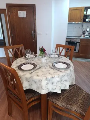 a table with two plates and wine glasses on it at Pirin View Apartment in Bansko