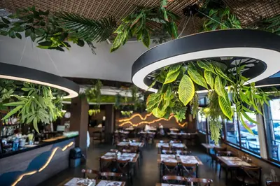 a restaurant with tables and plants hanging from the ceilings at Hotel Royal Bath in Banya