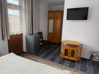 a bedroom with a television and a bed and a table at Къща за гости Гаджо Gadjo in Bansko