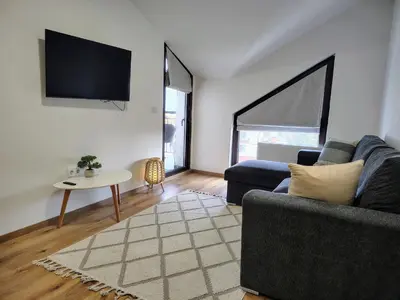 a living room with a couch and a tv at White Peak 2rooms ap in Bansko