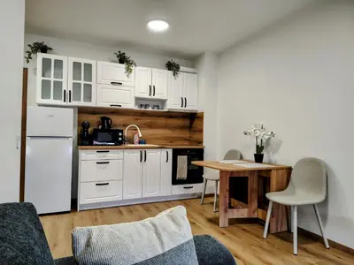 a kitchen with white cabinets and a wooden table at White Peak 2rooms ap in Bansko