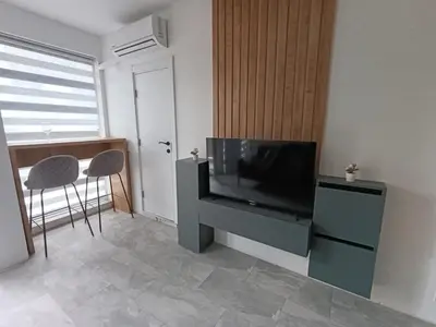 a living room with a television and a table with a stool at Green Apart Residence Including Parking Place in Sofia