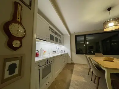 a kitchen with a table and a clock on the wall at Premium Studio Apartment in Private Villa Nisim in Batak