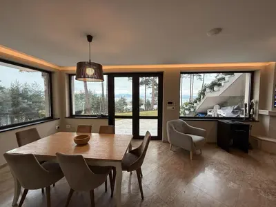 a dining room with a table and chairs and windows at Premium Studio Apartment in Private Villa Nisim in Batak
