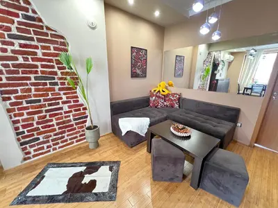 a living room with a couch and a brick wall at Hamburg 100 Sq M 2BDR Family Apt near NDK and Vitosha BLVD in Sofia
