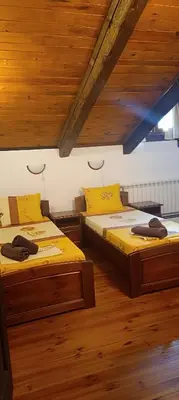 two twin beds in a room with wooden ceilings at Къща за гости- Шале Мила in Bansko