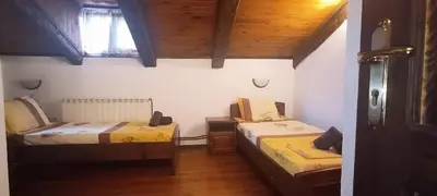 two beds in a room with wooden ceilings at Къща за гости- Шале Мила in Bansko