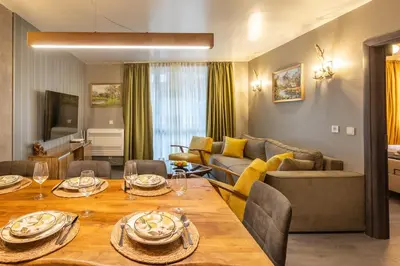 a living room with a dining table and a couch at Incredible 2BDR with Veranda and House-like Feel in Bansko