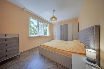 a bedroom with a bed and a dresser and a window at Oranssi Sunset - Free Parking in Sofia