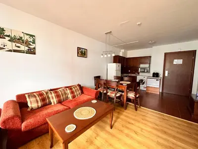 a living room with a couch and a table and a kitchen at Beby's Apartment - Tamplier in Bansko