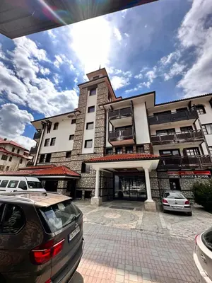 a building with cars parked in front of it at Beby's Apartment - Tamplier in Bansko