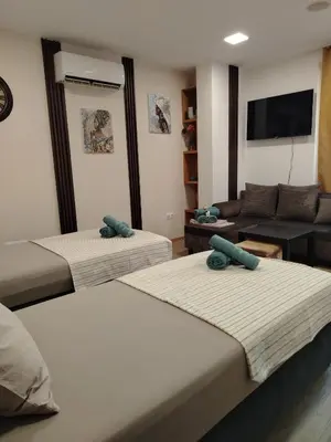 a hotel room with three beds and a couch at Good Mood Apartments & Parking 2 in Plovdiv