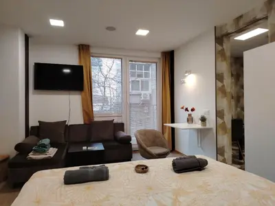 a bedroom with a large bed and a living room at Good Mood Apartments & Parking 2 in Plovdiv