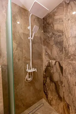 a shower in a bathroom with a stone wall at Elena apartment in Sandanski