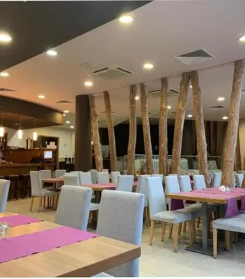 a restaurant with tables and white chairs and purple tables at Аспен голф ризорт F204 in Razlog