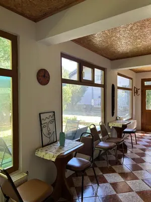 a dining room with tables and chairs and windows at Guest House Efrosina in Glozhene