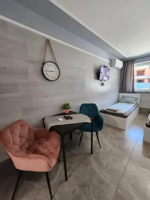 a living room with a table and a clock on the wall at Continental studios 4 in Sofia