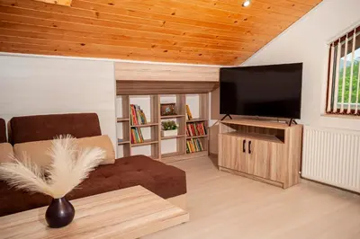 a living room with a couch and a flat screen tv at Къща за гости Крис in Smolyan