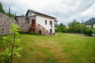 a house with a grass yard in front of it at Къща за гости Крис in Smolyan