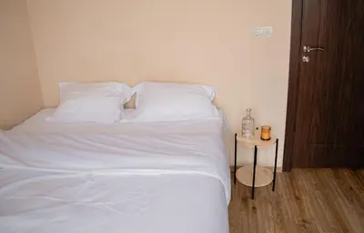 a bedroom with a bed with white sheets and a table at Paradise Nest in Sofia