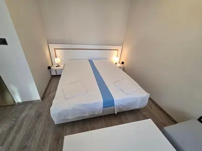 a large bed in a small room with two tables at Paradise Studio NBU in Sofia