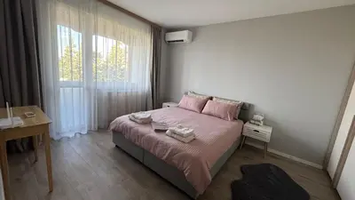 a bedroom with a bed with pink sheets and a window at Modern and cozy apartment in the city centre in Sofia