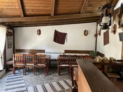 a dining room with wooden tables and chairs in a room at Kalaydzhiev Guest House - Къща с 5 спални in Bansko