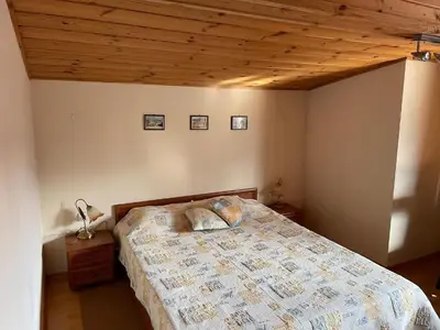 a bedroom with a bed with a wooden ceiling at Kalaydzhiev Guest House - Къща с 5 спални in Bansko