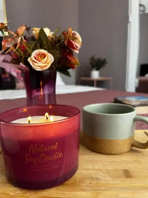 a candle and a cup and a vase with flowers at Rea Liliya - Artistic and Inviting Nook in Sofia