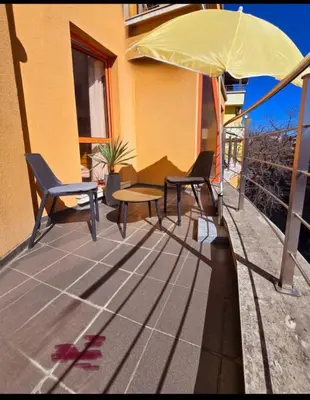a patio with two chairs and a table and an umbrella at Guest House Amaya by novotela in Plovdiv