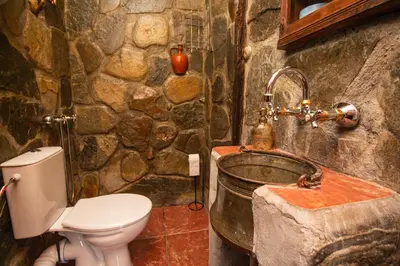 a stone bathroom with a toilet and a sink at Дедовата Къща in Dedovo