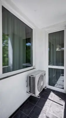 an air conditioner sitting on a porch next to two windows at Cosy & Modern 1BD Flat close to NDK by Flat Mаnager in Sofia