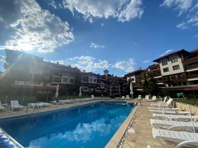 a swimming pool with lounge chairs and a building at Barosa Apartment Bansko Royal Towers in Bansko
