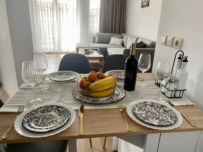 a table with plates and a bowl of fruit and wine glasses at Barosa Apartment Bansko Royal Towers in Bansko