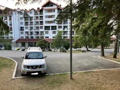 a white car parked in a parking lot in front of a building at Borovets Gardens apartment C-43 in Borovets