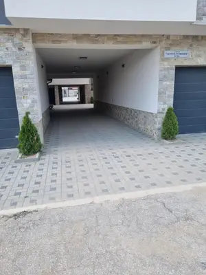 a garage with two garage doors and two bushes at Apartament Rumqncev in Velingrad