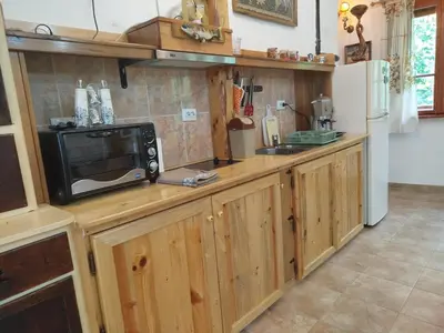 a kitchen with wooden cabinets and a microwave on a counter at Къща за гости Аврамови in Ribarica