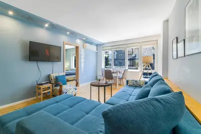 a living room with a blue couch and a tv at Charming Downtown Apartment with Unique Terrace in Sofia