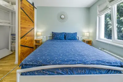 a bedroom with a bed with a blue comforter and two windows at Charming Downtown Apartment with Unique Terrace in Sofia