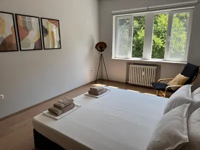 a bedroom with a white bed with two towels on it at By The River in Plovdiv