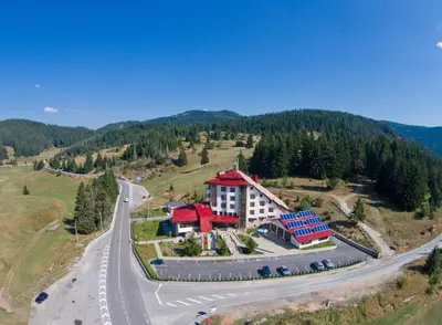 an aerial view of a building on a hill next to a road at Hotel Coop Rozhen in Pamporovo