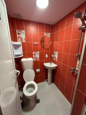 a red tiled bathroom with a toilet and a sink at Guest Rooms Comfort 2 in Plovdiv