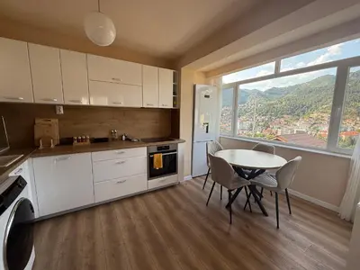 a kitchen with a table and chairs and a window at Нощувки 