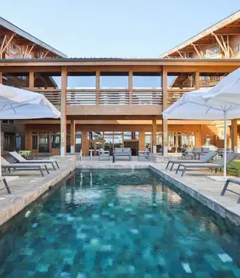 a pool with chairs and umbrellas in front of a building at Pirin Golf Spa Condo with Mountain View in Razlog