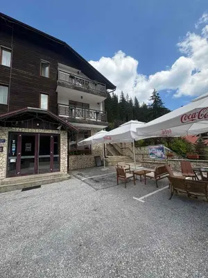 a building with benches and umbrellas in front of it at Pine forest apartments in Pamporovo