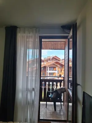 a window with a view of a balcony with a chair at Илен C411 Panorama Resort Bansko in Bansko