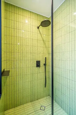 a bathroom with a shower with yellow tiles at Bright & Central 2BR in Historic Heart of Sofia in Sofia
