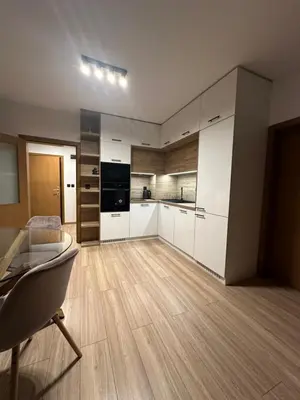 a kitchen with white cabinets and a wooden floor at K&D Alpine Getaway , Cozy Stay in Bansko