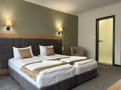 a bedroom with a large bed and a chair at Hotel Odrys in Plovdiv