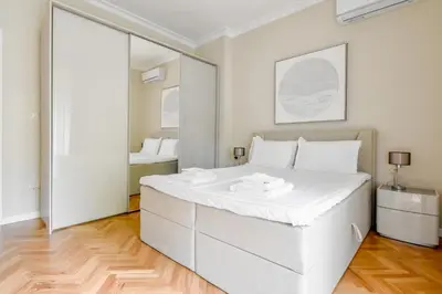 a white bedroom with a large white bed and a mirror at Designer 2BD Apt Near Alexander Nevski Cathedral by Flat Mаnager in Sofia